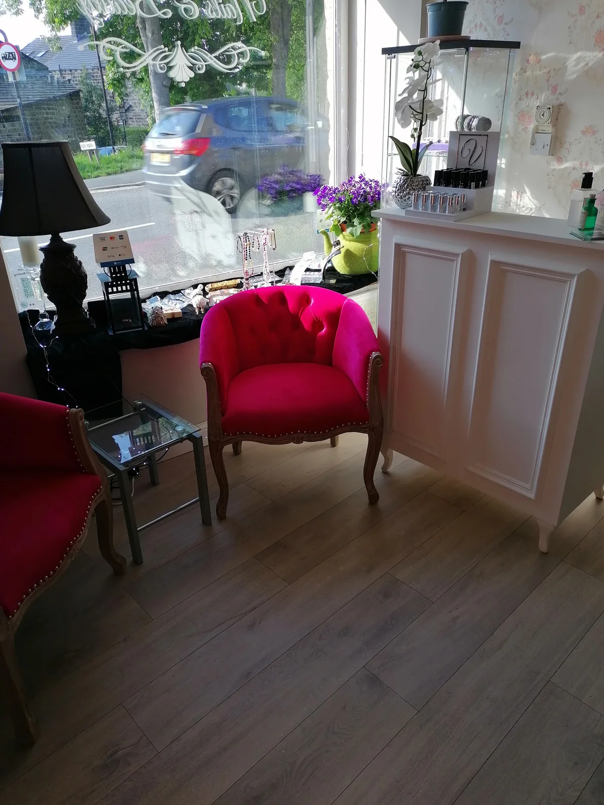 A pink velvet chair, nail colour displays and daylight in the salon